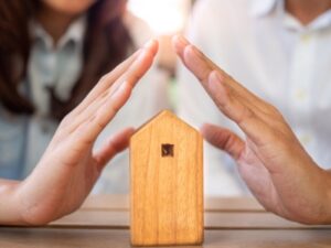 couples hands over wooden house to show non-probate assets like jointly owned property can cause probate delays