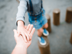 child holds adult hand in park- designate a guardian legal checklist concept